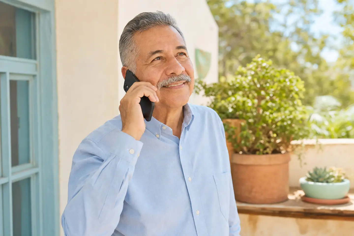 Hombre de unos sesenta años hablando por celular en su casa